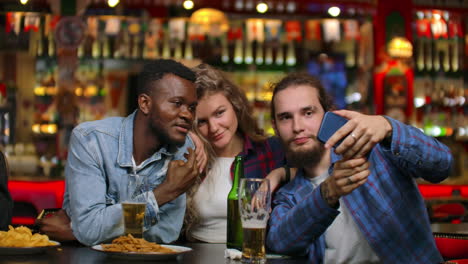 Three-friends-two-Europeans-and-African-American-men-are-photographed-together-while-sitting-in-a-beer-bar.-Multinational-company-of-friends.